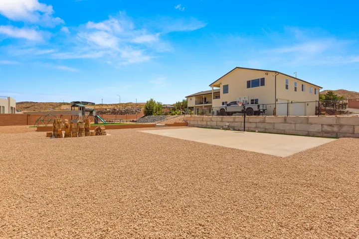 Expansive gravel yard featuring a concrete sports court and a dedicated play area with artificial turf