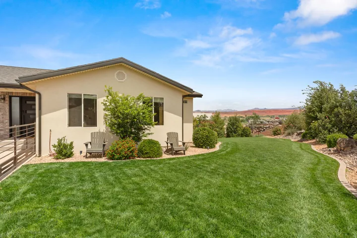 Spacious rear yard featuring an expansive lawn, mature landscaping, and a desert mountain backdrop