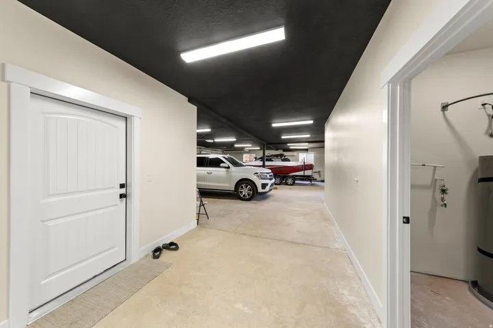 Large garage space with light concrete flooring, white painted walls, and a black painted ceiling