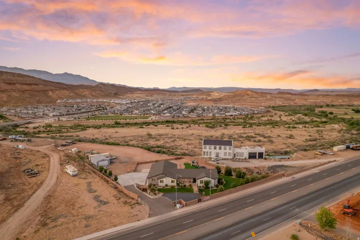Expansive property featuring a modern two-story residence with a detached garage building, perimeter fencing, and established landscaping