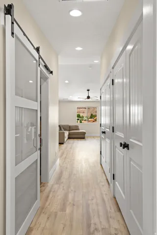 Hallway featuring wood-finish flooring, white paneled doors, and recessed lighting
