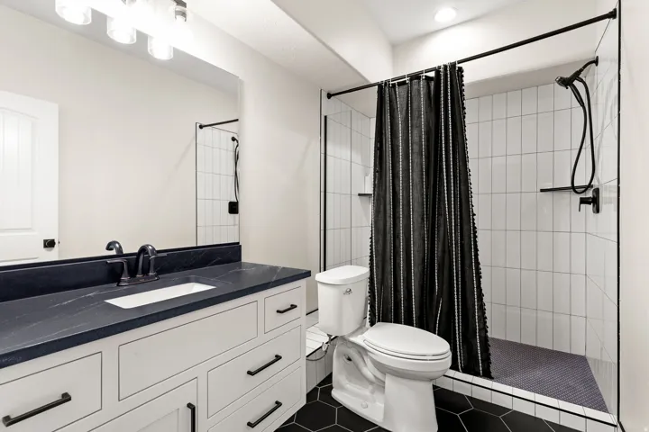 Bathroom featuring a white vanity with dark stone countertop, undermount sink, and matte black hardware