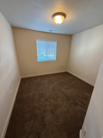 756-Brown carpeted room featuring light beige walls and white baseboards