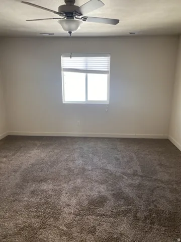 750-Spacious room featuring neutral carpeting, a single window with blinds, and a ceiling fan with integrated lighting