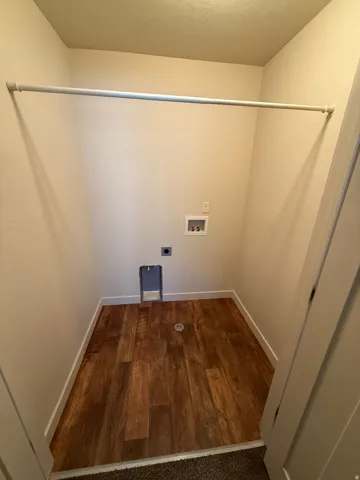 756-Dedicated laundry area featuring wood-finish flooring, white baseboards, and a wall-mounted hanging rod