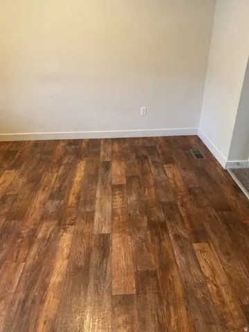 750-Vinyl flooring with varied warm tones, complemented by crisp white baseboards and light-colored wall paint