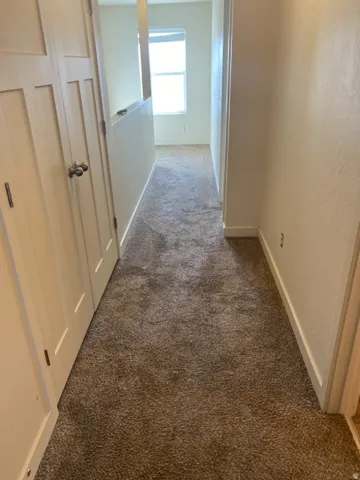 750-Hallway featuring neutral-toned carpeting, light-colored walls, and a window providing natural light at the far end