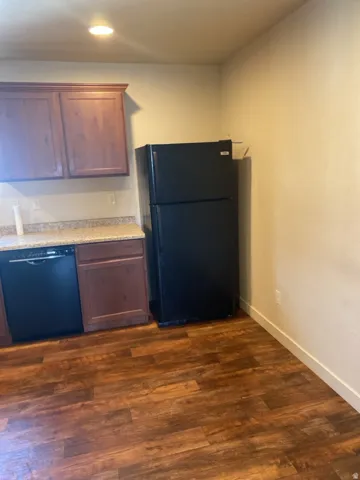 750-Kitchen area featuring wood-finish flooring, dark wood cabinetry, and speckled countertops