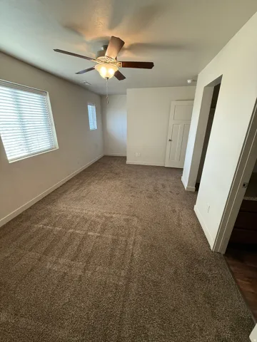 756-Spacious room with plush brown carpeting, a multi-paneled door, and a ceiling fan with integrated lighting