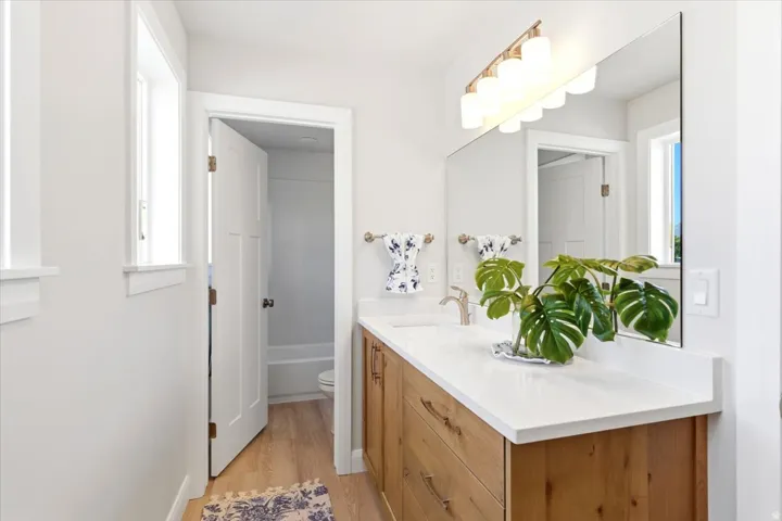 Bathroom featuring a wood-finish vanity with drawer storage, a white countertop, and an undermount sink with a single-handle faucet