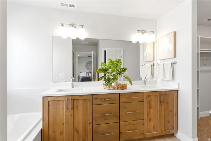 Dual vanity with wood-finish cabinetry, white countertops, and undermount sinks