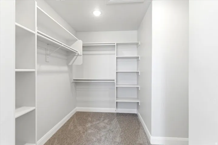 Walk-in closet featuring built-in shelving, white hanging rods, and recessed lighting