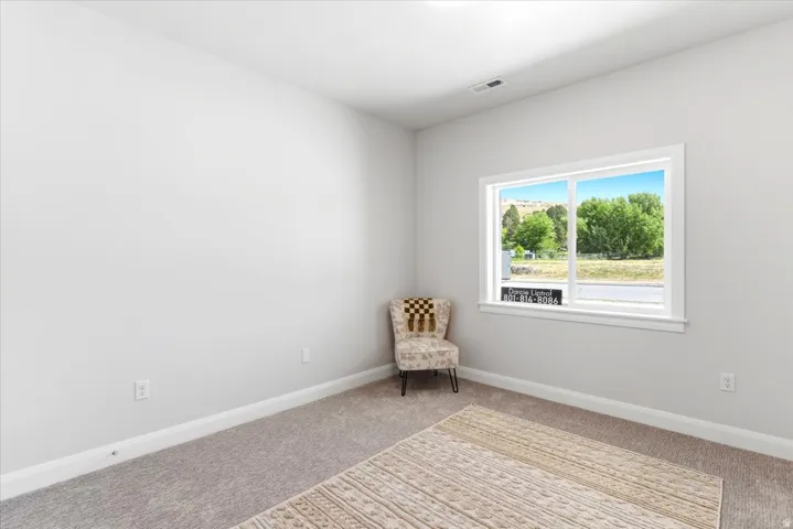 Room featuring light gray wall paint, white trim, gray carpet flooring, and a large window with a natural landscape