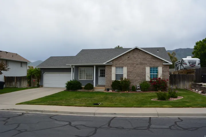 Single-story residence featuring a brick facade with light-colored shutters, an attached garage, and a covered front entry