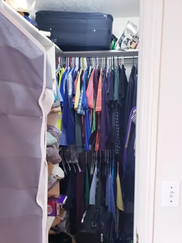 Walk-in closet featuring white painted shelving, double hanging rods, and an upper storage shelf