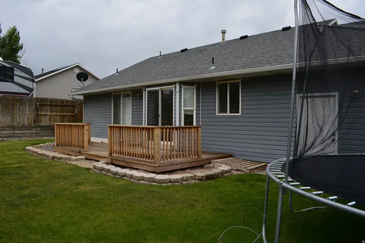 Rear exterior featuring gray horizontal siding, a composite shingle roof, and a wooden deck with railing
