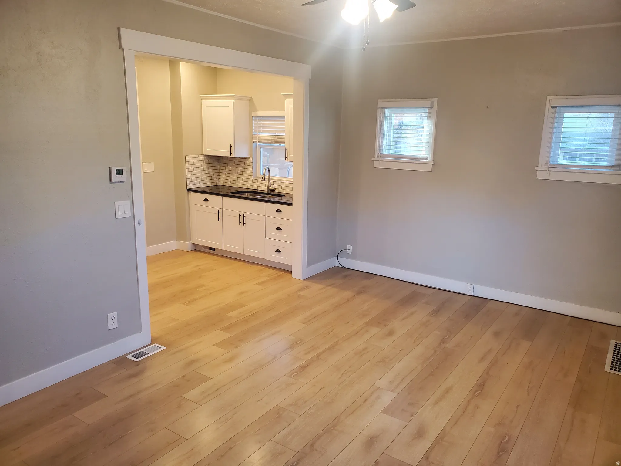 Open concept living space featuring wood-finish flooring and two windows with blinds