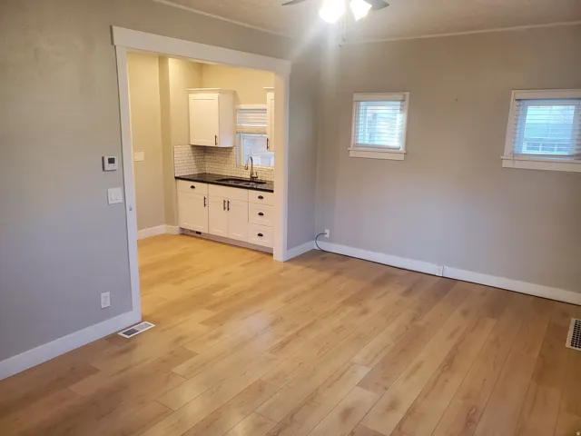 Open concept living space featuring wood-finish flooring and two windows with blinds
