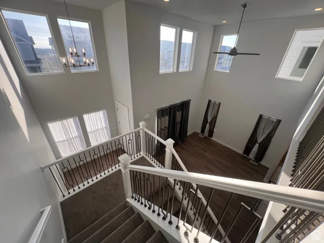 Two-story interior with white walls featuring an open stairwell with black iron balusters, wood-finish flooring, and multiple high-set windows