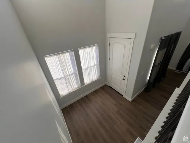 Entryway featuring wood-finish flooring, a white paneled door with polished hardware, and two tall windows with white window treatments