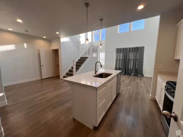 Open-concept living space with a central kitchen island featuring a stainless steel sink and modern pendant lighting