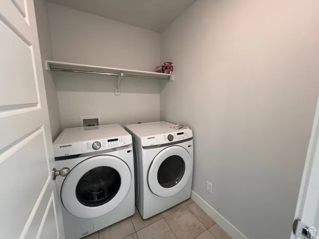 Dedicated laundry area featuring tile flooring and a built-in shelving unit with hanging rod