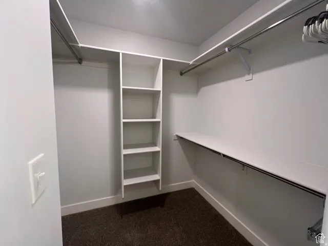 Spacious walk-in closet featuring white built-in shelving, multiple hanging rods, and ample storage space