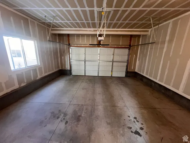 Garage space featuring a concrete floor, a white sectional garage door, and a single window