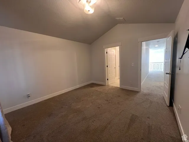 Carpeted room with vaulted ceiling and two white paneled doors