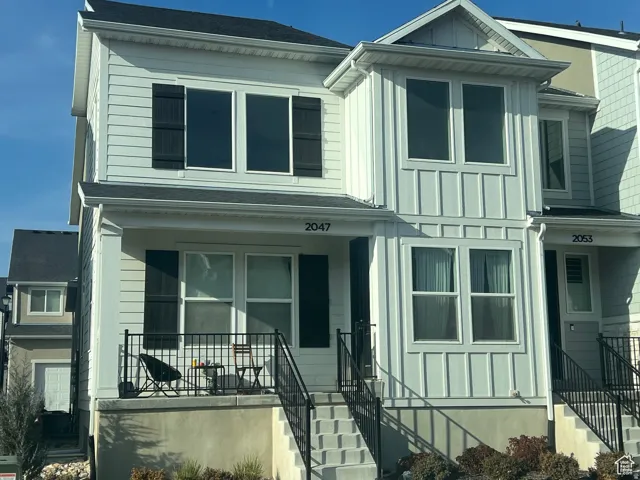 Light-colored two-story townhouse with horizontal siding and board and batten accents