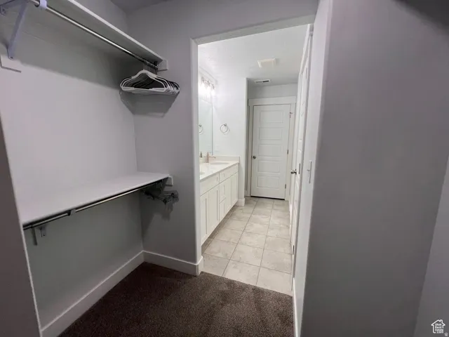 Walk-in closet with carpet flooring, white shelving, and hanging rods