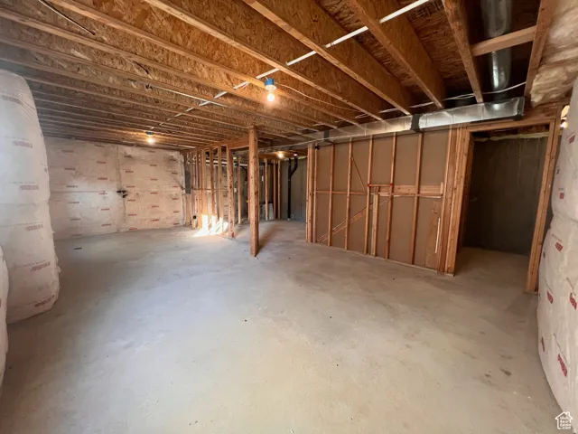 Unfinished basement featuring exposed wood ceiling joists, concrete flooring, and framed interior walls