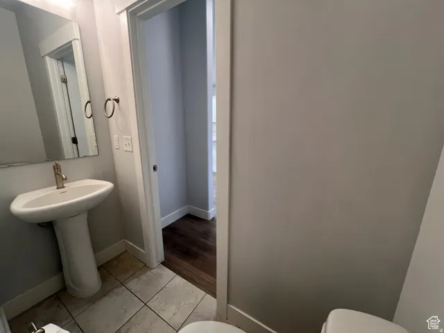 Pedestal sink with brass-finish faucet, framed mirror, and tile flooring