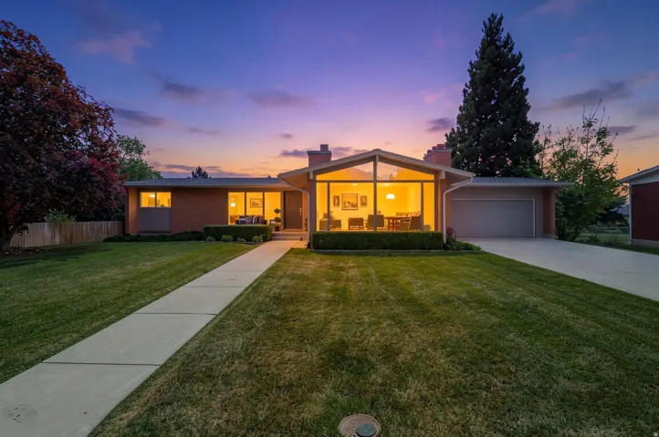 Mid-century modern residence featuring a striking A-frame window design, brick facade, and an attached garage