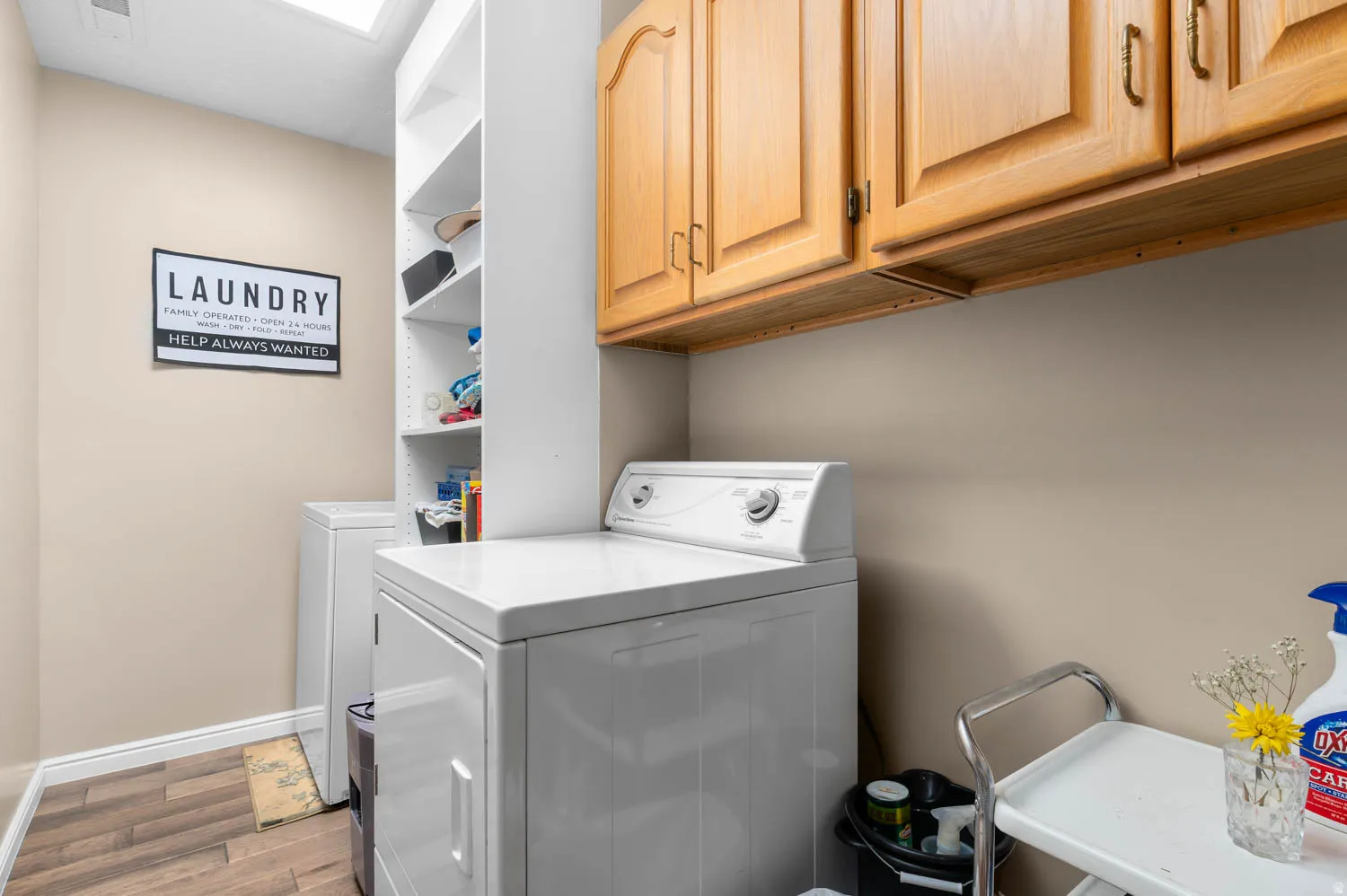 Dedicated laundry area featuring wood-finish flooring, ample built-in cabinetry, and integrated shelving for storage