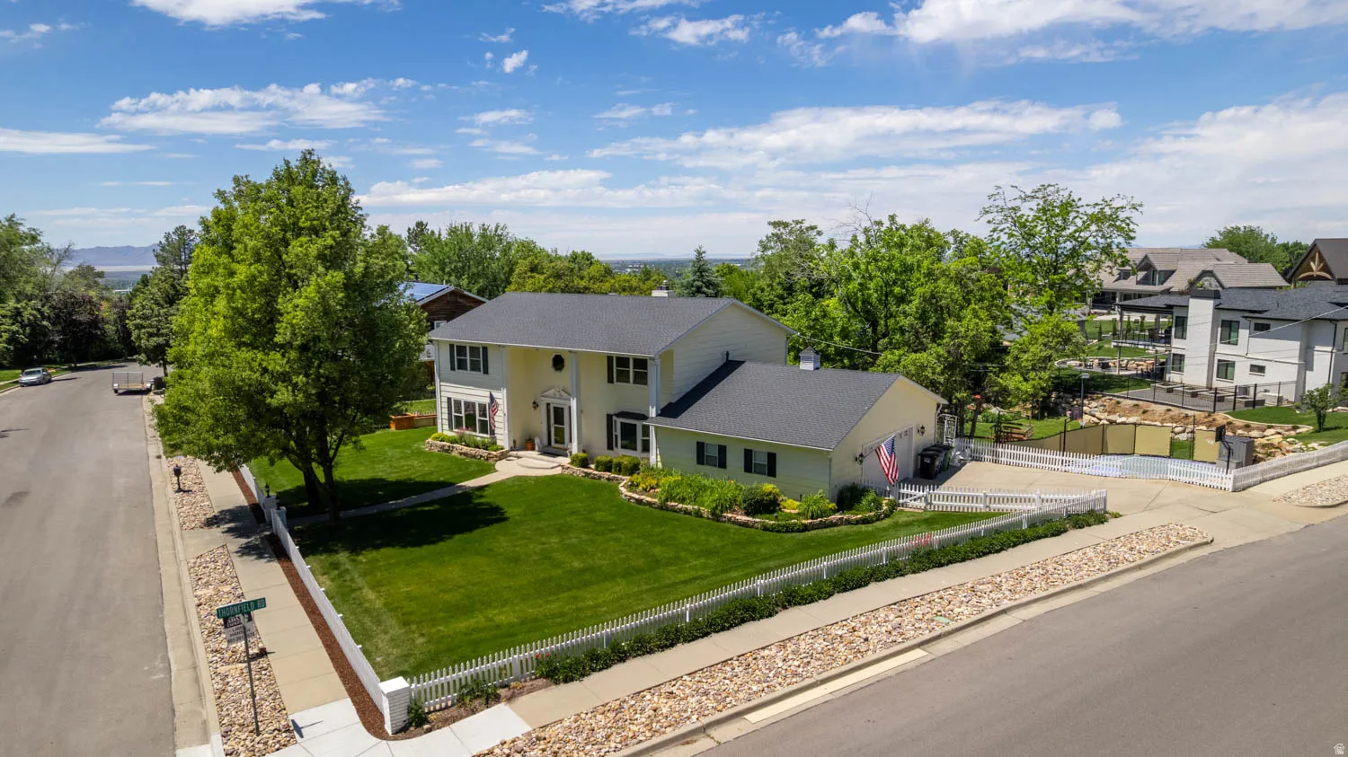 Two-story residence featuring a light-colored exterior and dark shingle roof