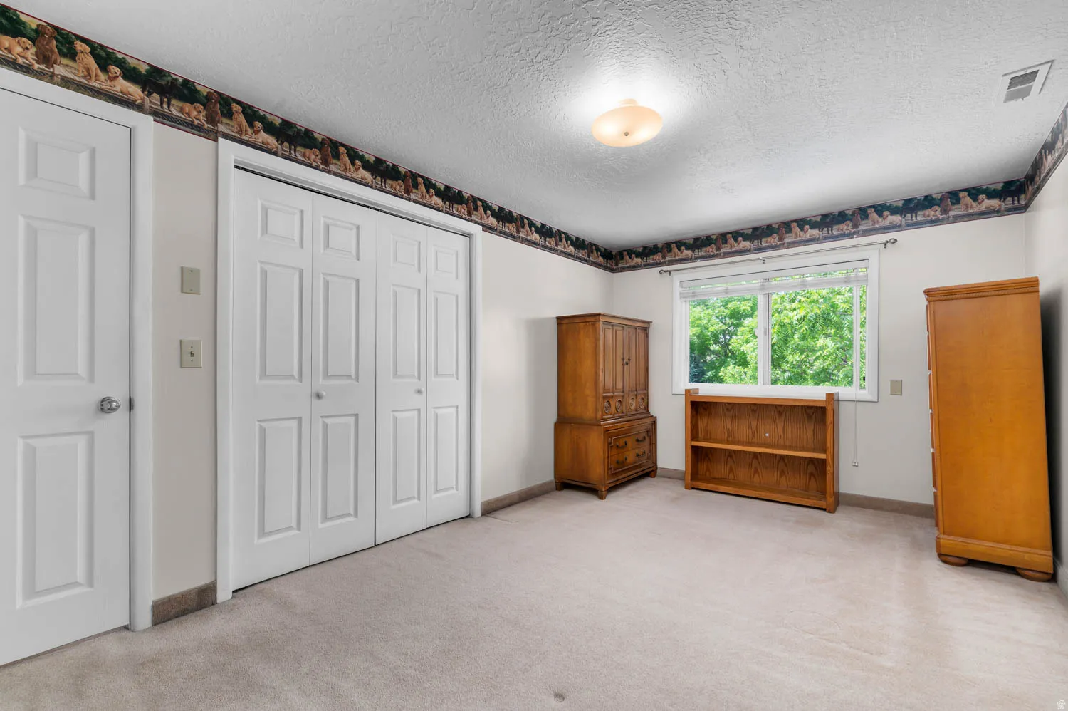 Neutral-toned carpeting spans the room, complemented by white walls and a patterned border