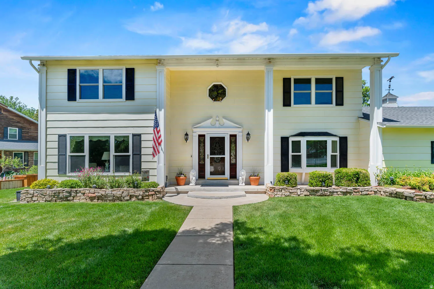 Two-story home with a light-colored exterior and black shutters