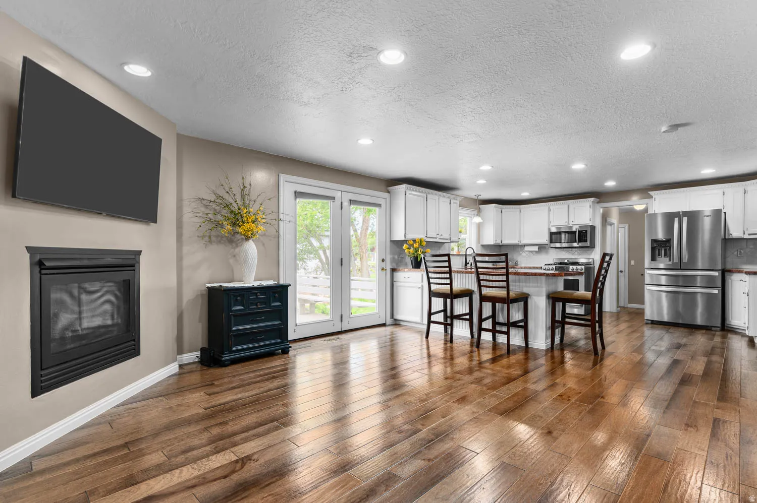 Open-concept living space featuring wood-finish flooring, recessed lighting, and a built-in fireplace