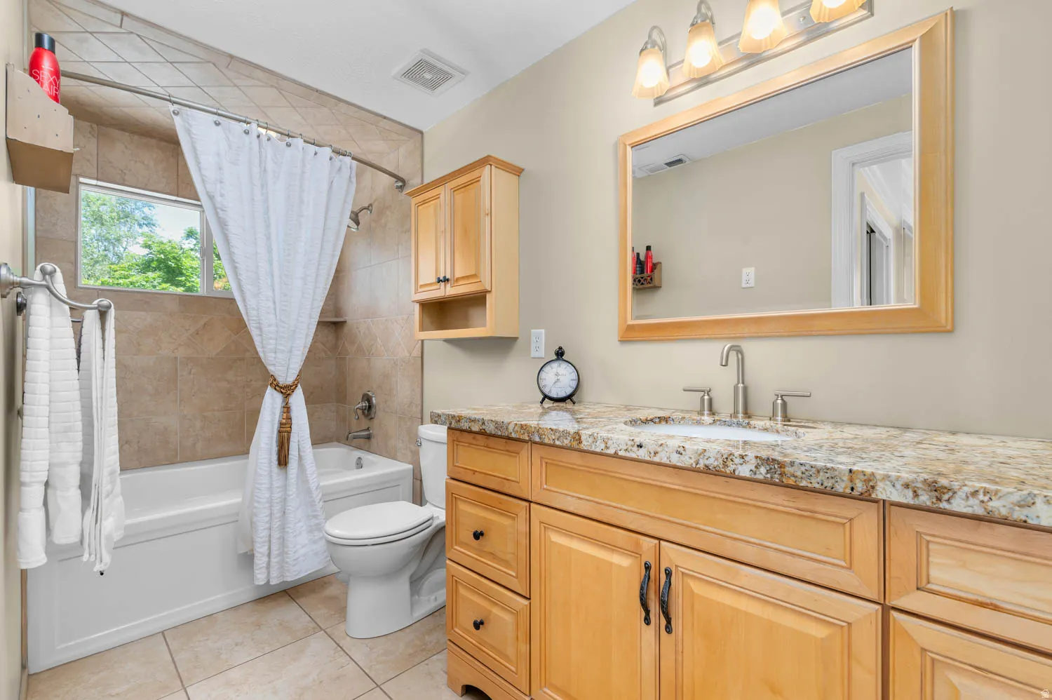 Bathroom with a built-in tub and tiled shower surround, featuring a window and recessed shelf