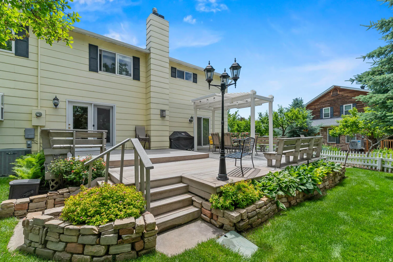 Multi-level rear deck with pergola, stone retaining walls, and planted greenery