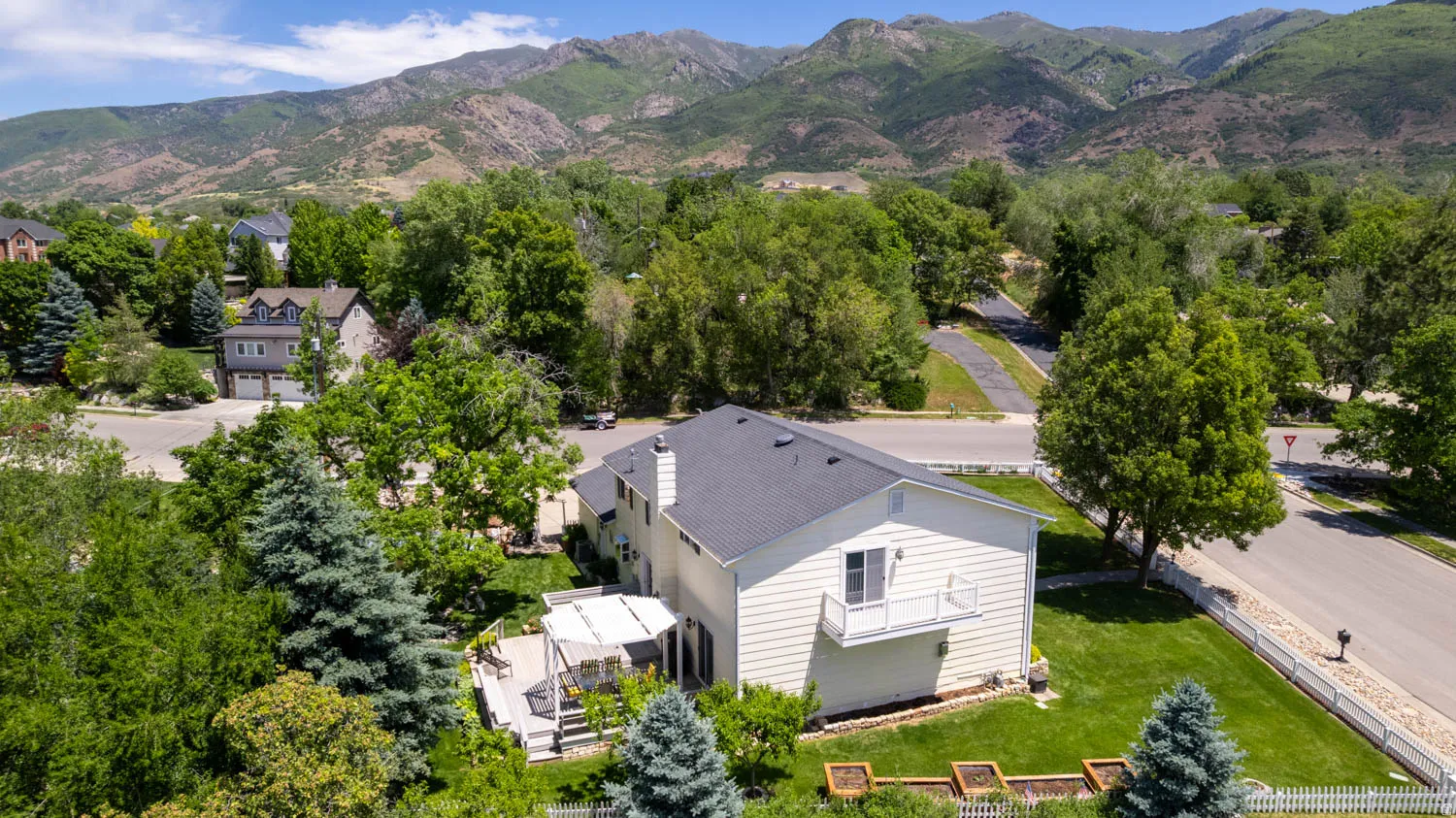 Two-story property featuring a rear deck with a pergola, a second-story balcony, and mature landscaping