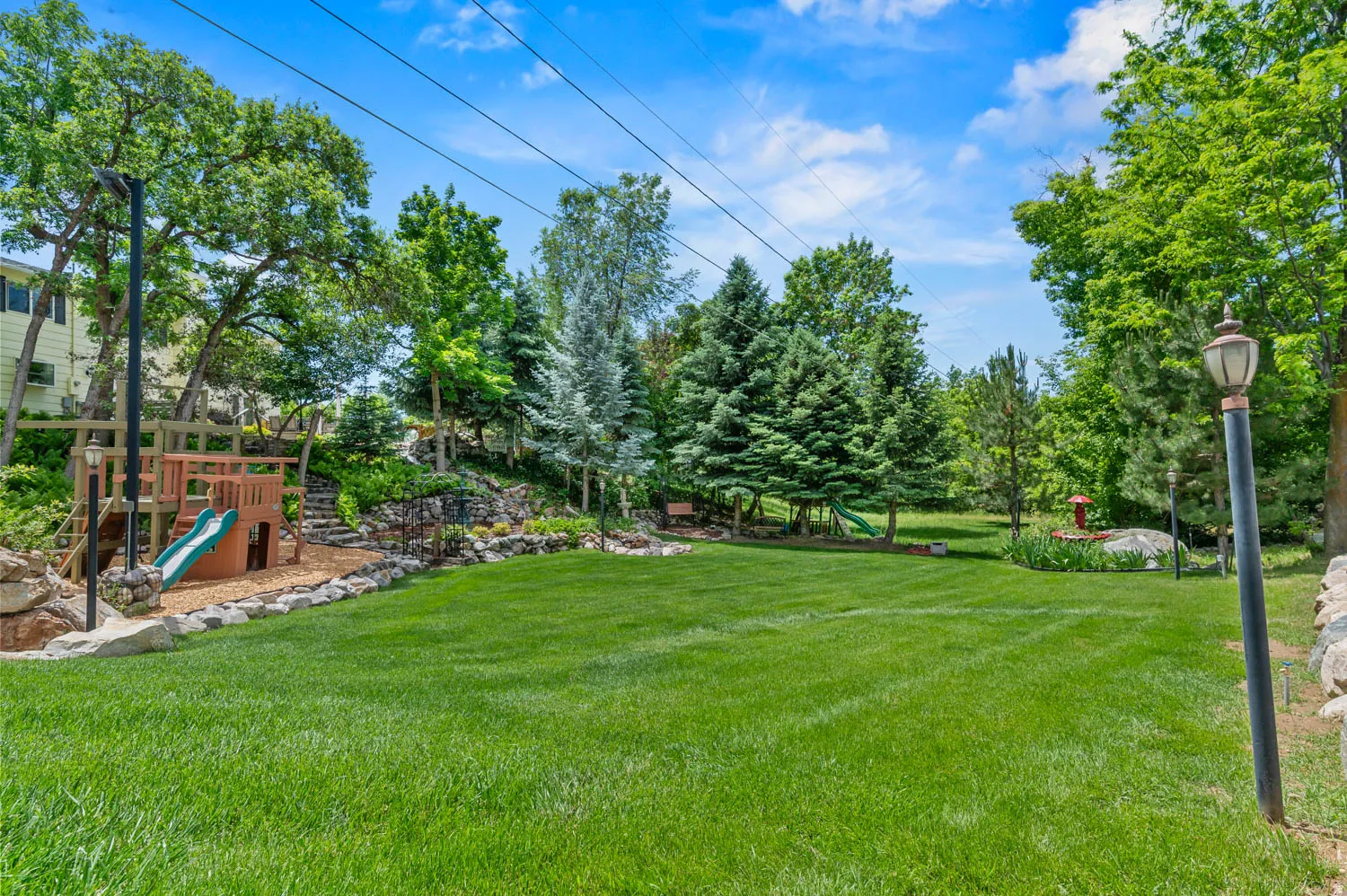 Expansive lawn area featuring established trees and a rock-lined border