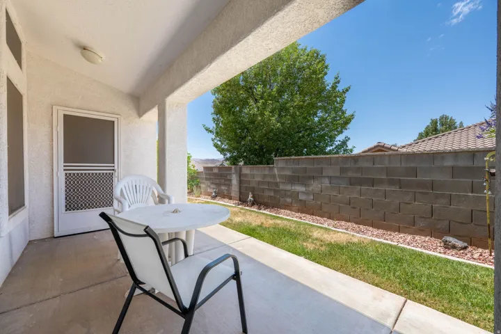 Covered patio with a concrete slab, exterior lighting, and a screen door