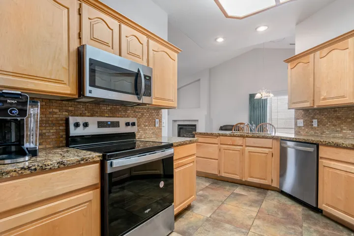 Kitchen featuring wood cabinetry, granite-finish countertops, and a mosaic tile backsplash