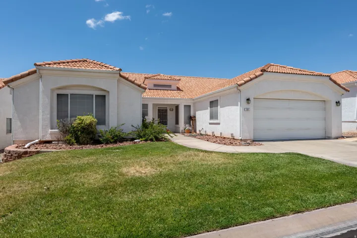 Stucco exterior featuring a two-car garage, concrete driveway, and a tile roof