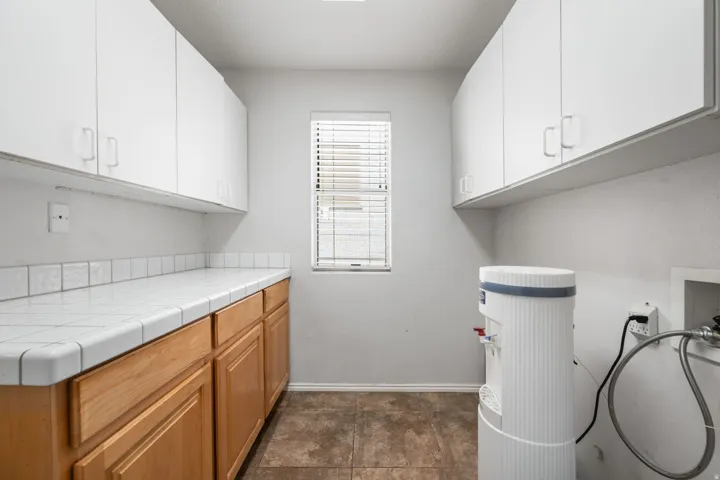 Utility space featuring extensive white upper cabinetry and wood-finish lower cabinetry