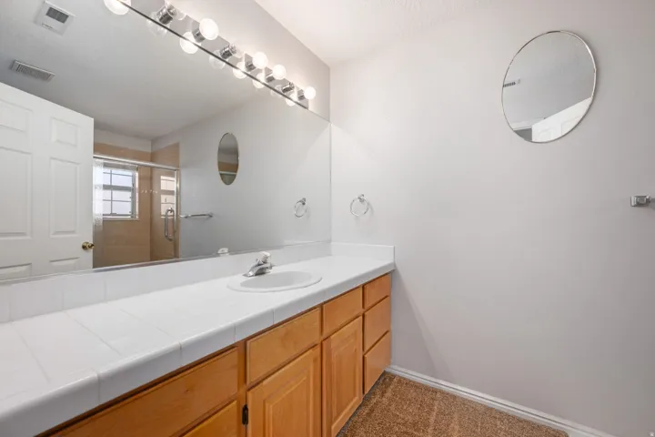Bathroom vanity featuring a single sink, light wood cabinetry, and a white tile countertop