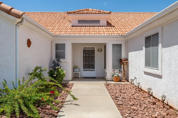 Entryway featuring a white stucco exterior, terracotta tile roof, and a concrete pathway