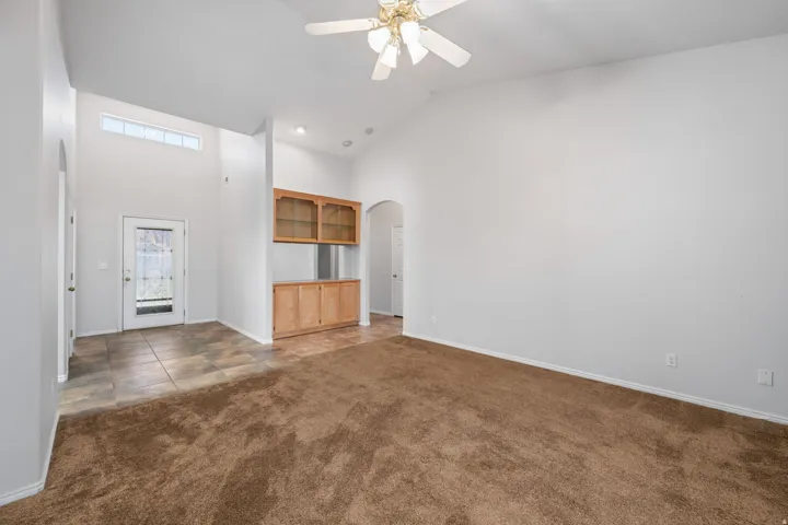Vaulted ceilings define this space, featuring a ceiling fan with integrated lighting